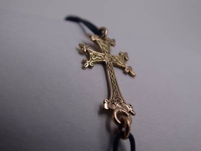 Croix Arménienne, en or 18 carats.0.98 gramme, montée sur cordon Noir tressé.